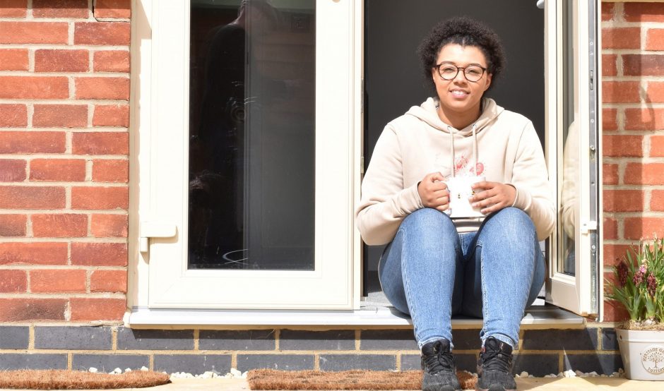 girl sat on step outside house with mug in hand