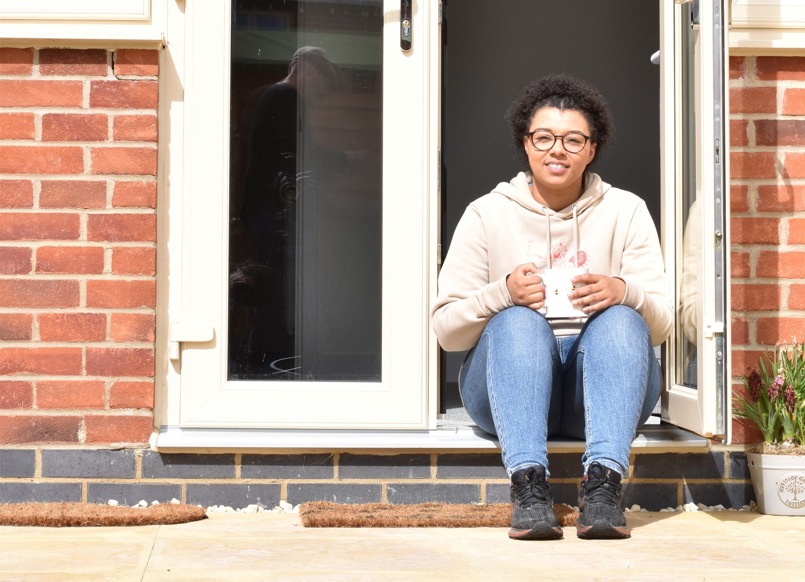 girl sat on step outside house with mug in hand